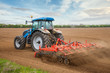 Small scale farming with tractor and plow in field