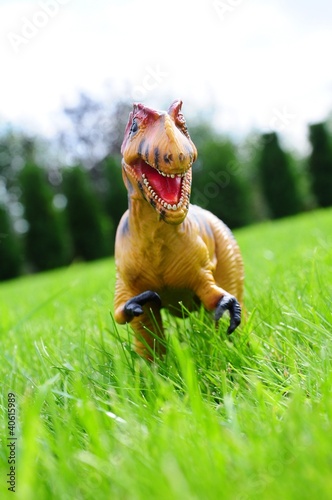 Photo: dinosaur toy on grass dinosaur toy on grass