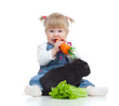 Smiling little girl eating a carrot and feeding rabbit with lett