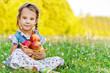 little girl sitting on grass with basket of apples