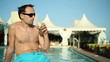Young man having a drink by the pool
