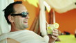 Young smiling man drinking exotic cocktail in luxury bar