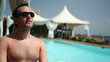 Happy young man sunbathing by the luxury swimming pool