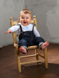 Baby sitzt auf einem Stuhl und freut sich Baby sitzt auf einem Stuhl und freut sich