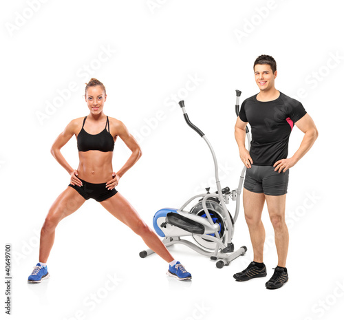 Foto: Female and male athletes posing next to a cross trainer machine Female and male athletes posing next to a cross trainer machine