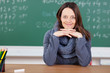 lächelnde lehrerin sitzt am pult