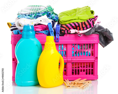 Photo: Clothes with detergent in pink plastic basket isolated on white Clothes with detergent in pink plastic basket isolated on white