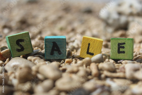 Photo: The word SALE written on wooden cubes, at the beach The word SALE written on wooden cubes, at the beach