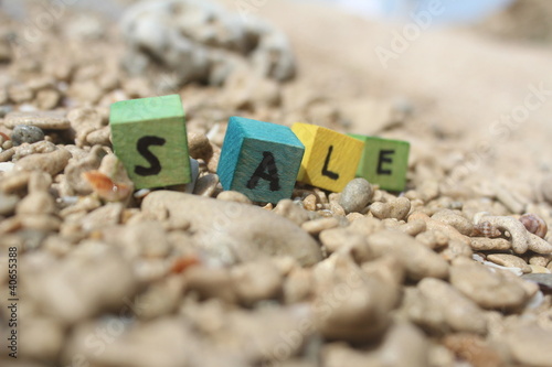 Photo: The word SALE written on wooden cubes, at the beach The word SALE written on wooden cubes, at the beach