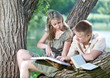 Young guy and the girl with textbooks on the bank of lake Young guy and the girl with textbooks on the bank of lake