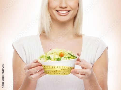 Foto: A young blond woman holding a fresh green salad A young blond woman holding a fresh green salad