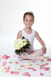 Young ballerina sitting with a bunch of flowers