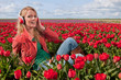 Dutch blond girl with headphones  in field with tulips