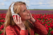 Dutch blond girl with headphones in field with tulips Dutch blond girl with headphones in field with tulips