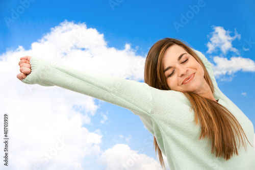 Photo: Young woman stretching arms outdoors. Young woman stretching arms outdoors.