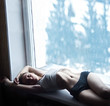 young woman with a beautiful body lies near the window