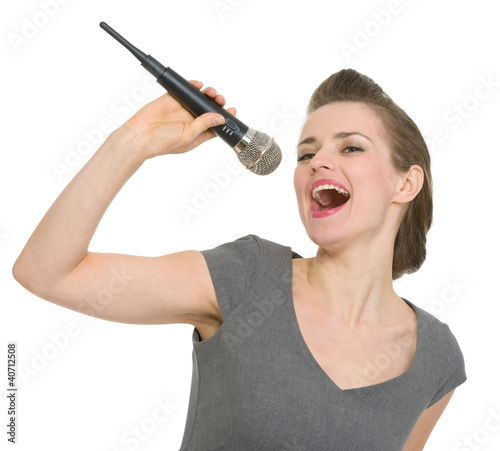 Photo: Cheerful woman singing in microphone isolated Cheerful woman singing in microphone isolated