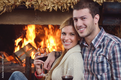 Photo: Young romantic couple relaxing in front of fireplace at home Young romantic couple relaxing in front of fireplace at home