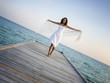 Sexy happy woman in white clothes standing on a jetty (Maldives)