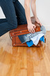 Photo: Woman trying to close suitcase with too much clothing Woman trying to close suitcase with too much clothing