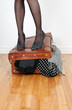 Photo: Woman in high heel shoes standing on overfilled suitcase Woman in high heel shoes standing on overfilled suitcase