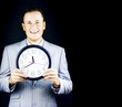 Smiling man in gray suit holding a clock Smiling man in gray suit holding a clock