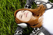 Young fashion girl with headphones lying at green spring grass.