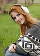 Young fashion girl with headphones sitting at green spring grass