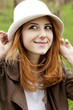 Young fashion girl in whte hat at green spring grass.