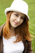 Young fashion girl in whte hat at green spring grass.