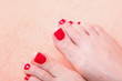 woman feet with red toenails on towel