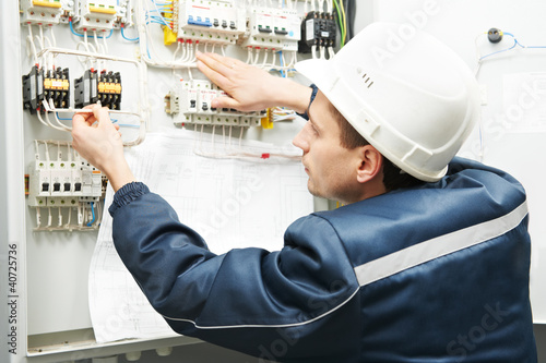 Photo: Electrician with drawing at power line box Electrician with drawing at power line box