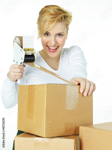 Photo: Pretty woman at work wraps up a packet for delivery Pretty woman at work wraps up a packet for delivery