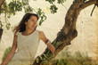 Beautiful girl in white dress sitting on the tree. Photo in old