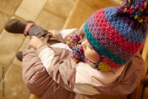 Photo: Young Girl Sitting On Wooden Seat Putting On Warm Outdoor Clothe Young Girl Sitting On Wooden Seat Putting On Warm Outdoor Clothe