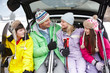 Teenage Family Sitting In Boot Of Car With Skis