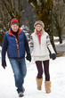 Couple Walking Along Snowy Street In Ski Resort