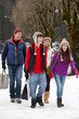 Teenage Family Carrying Shopping Walking Along Snowy Street