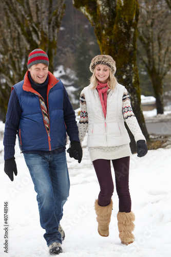 Foto: Couple Walking Along Snowy Street In Ski Resort Couple Walking Along Snowy Street In Ski Resort