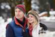 Couple Walking Along Snowy Street In Ski Resort Couple Walking Along Snowy Street In Ski Resort
