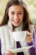 Teenage Girl In Outdoor CafŽ With Hot Drink  Wearing Winter Clot