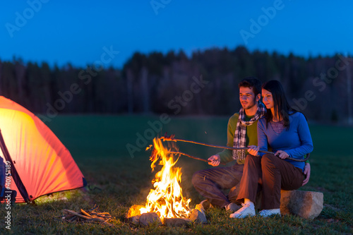 Photo: Camping night couple cook by campfire romantic Camping night couple cook by campfire romantic