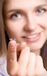 A girl holds a contact lens