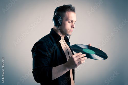 Photo: Young man working as dj with ear-phones and disc. Young man working as dj with ear-phones and disc.
