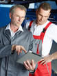 Motor mechanics inspecting the engine of a car with touchpad