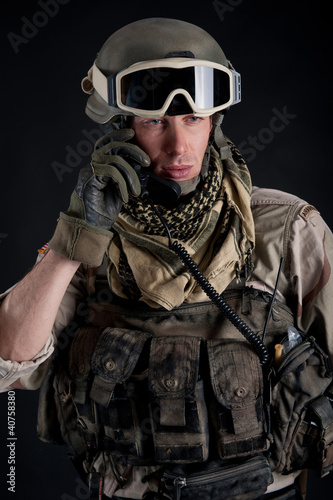 Photo: Soldier talking at the radio against black background. Soldier talking at the radio against black background.