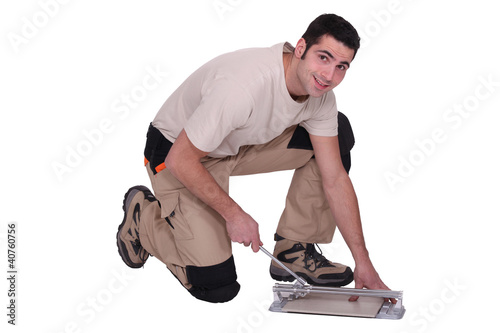 Photo: Man kneeling to cut tile to size Man kneeling to cut tile to size