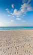 Foto: sandy beach with lots of footprints and a blue sky with clouds sandy beach with lots of footprints and a blue sky with clouds