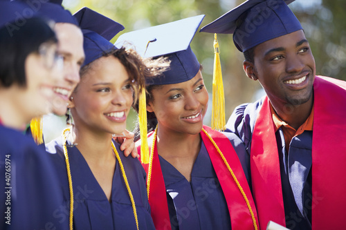 Photo: Graduates smiling together in cap and gown Graduates smiling together in cap and gown