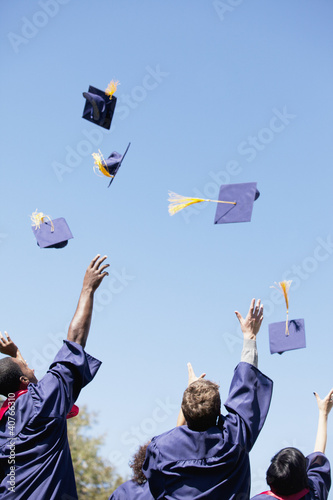 Photo: Graduates throwing caps in air outdoors Graduates throwing caps in air outdoors